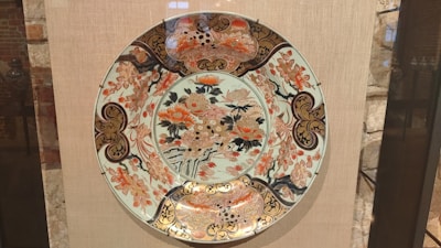 Close-up of handcrafted terracotta ceramic plate with intricate floral motifs inspired by Nusantara tradition.