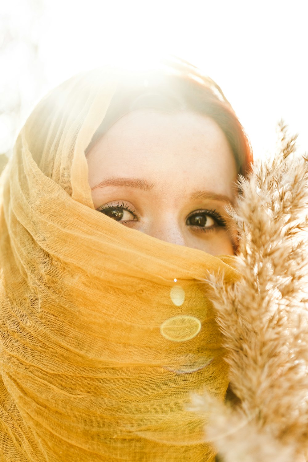 a woman with a yellow scarf covering her face