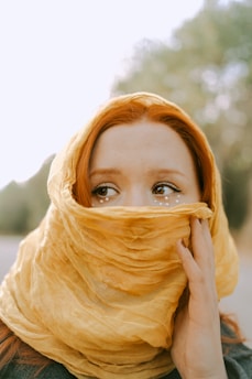 a woman wearing a yellow scarf covering her face