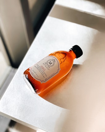 A bottle of Voulg Pharma's rich, amber-colored liver syrup with fresh herbs around it.