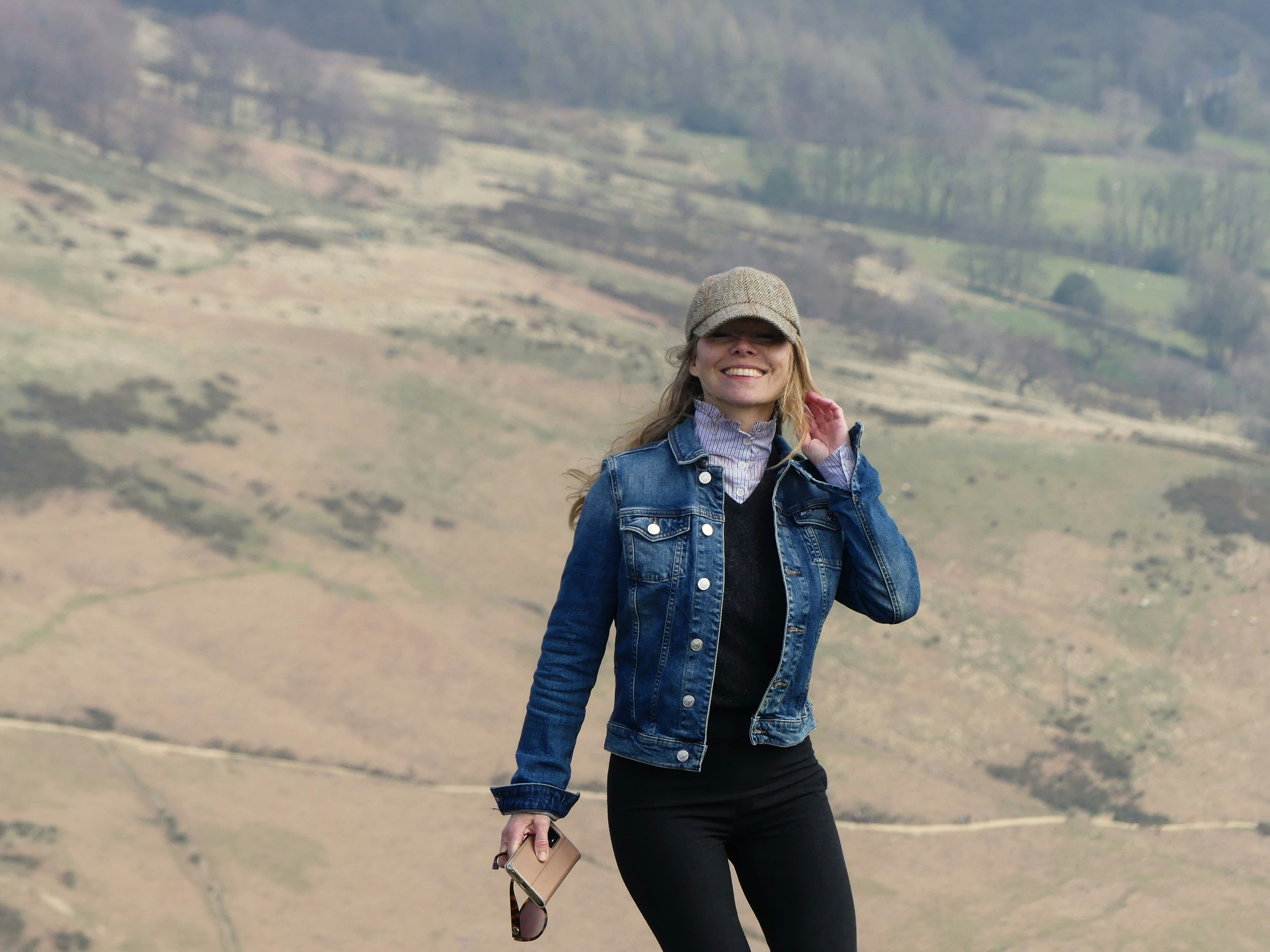 a woman in a denim jacket and hat is talking on a cell phone