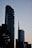 Two modern skyscrapers dominate the skyline against a fading twilight backdrop. The buildings have a sleek and contemporary architectural design, with the structure on the right displaying a logo featuring the name UniCredit. The scene is silhouetted by nearby trees which are partially visible, adding depth to the urban landscape.