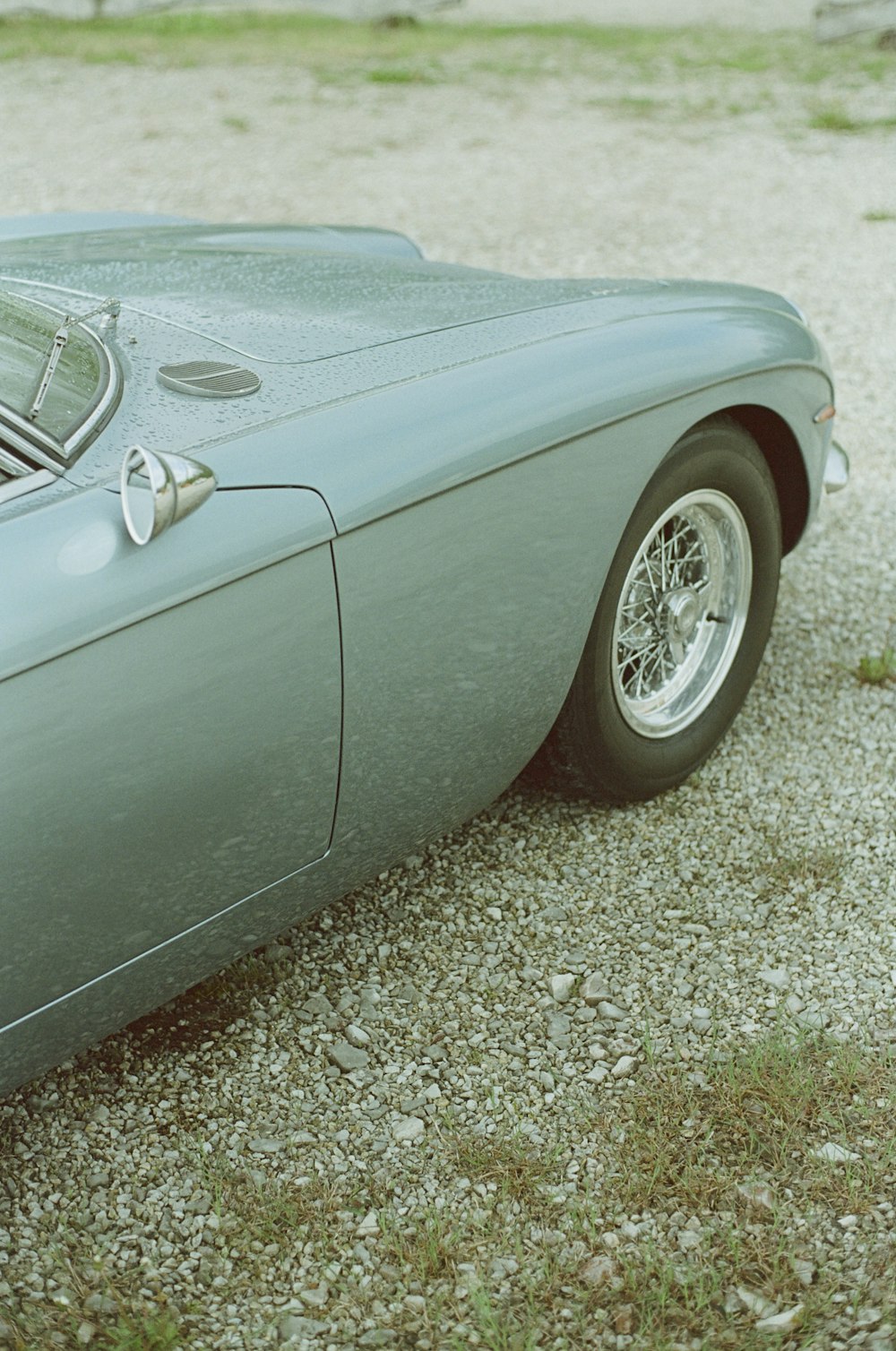 a blue sports car parked on a gravel road