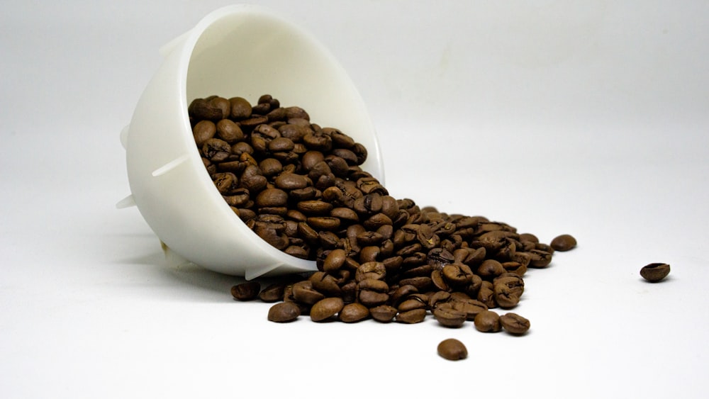 a white coffee cup filled with coffee beans