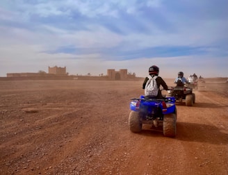 a group of people riding four wheelers on a dirt road