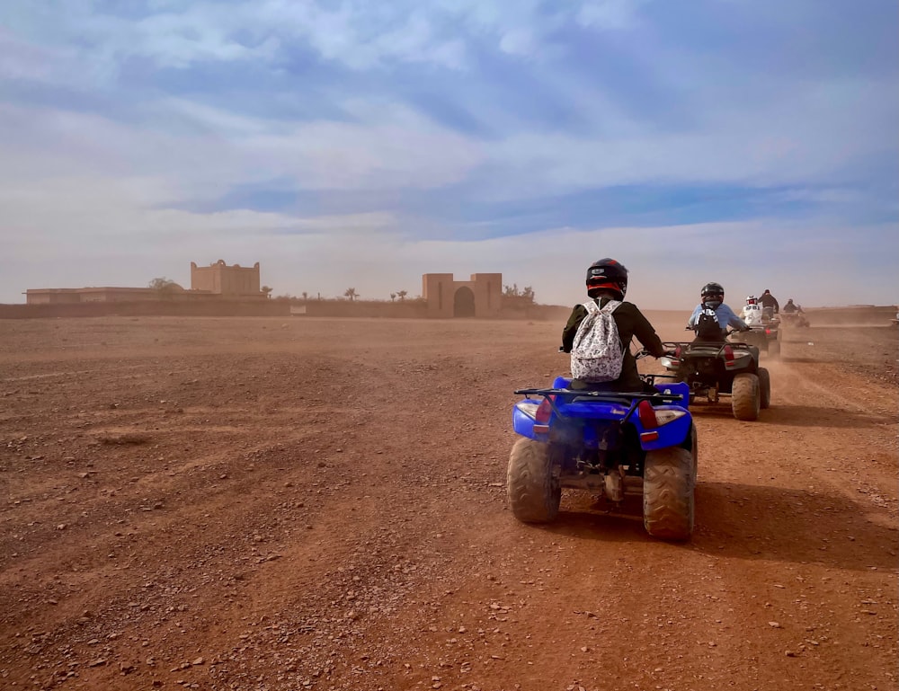 a group of people riding four wheelers on a dirt road
