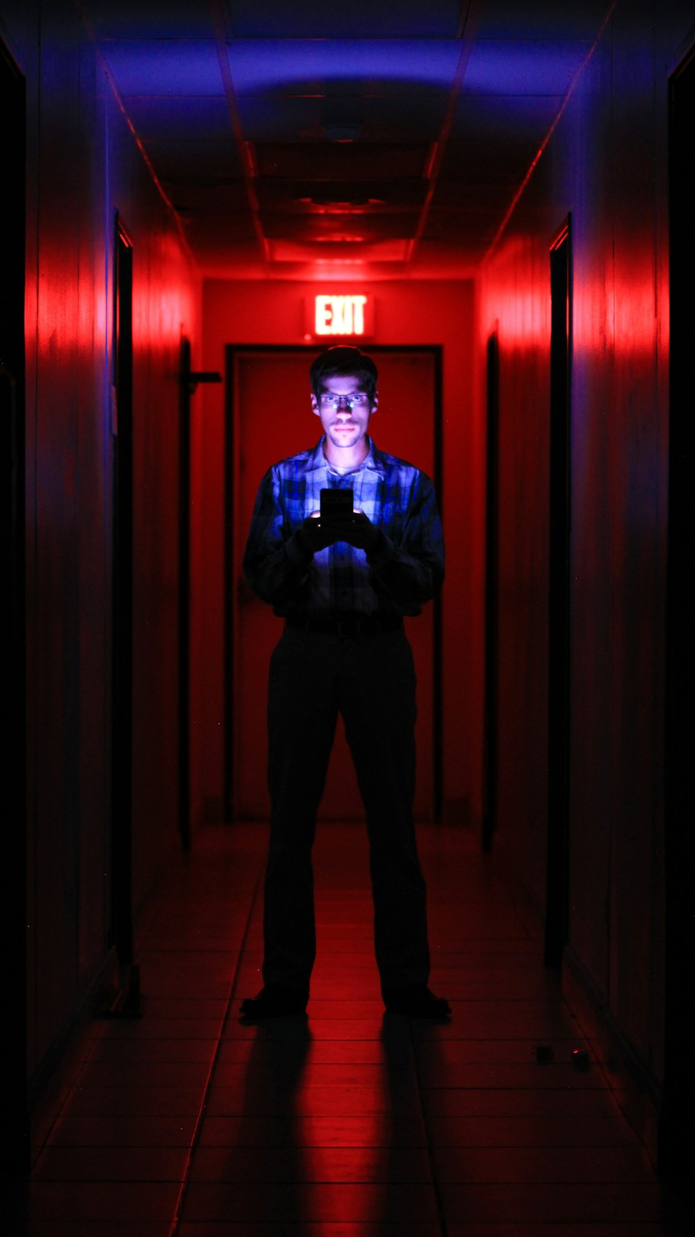 a man standing in a hallway with a cell phone