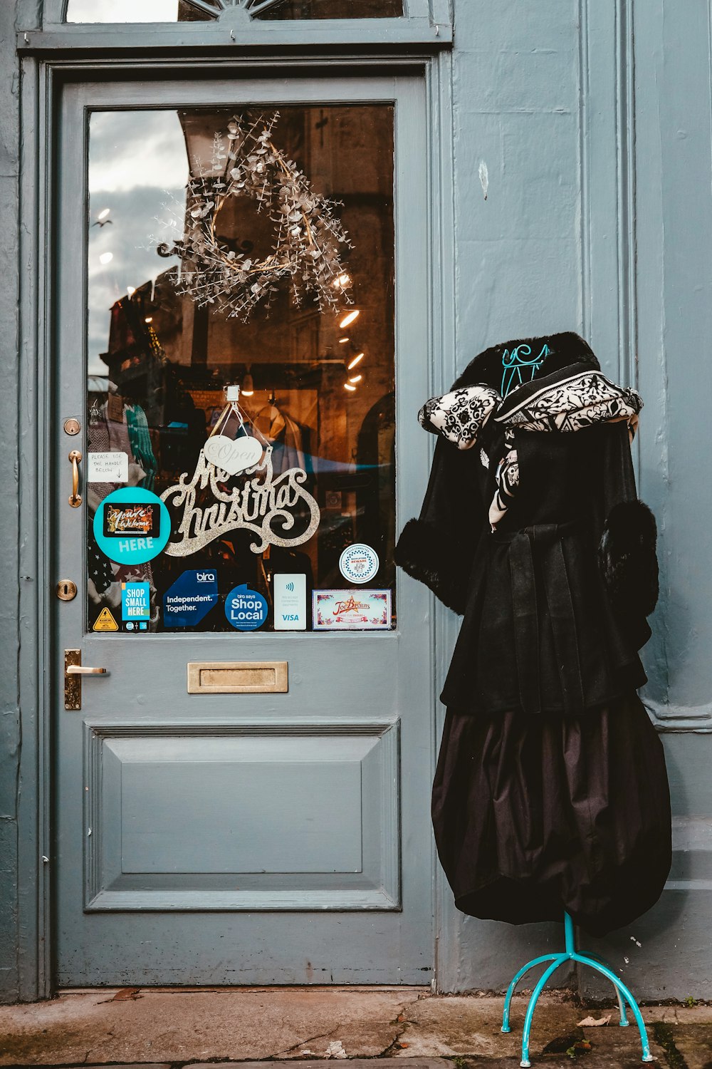 a blue door with a black dress and a hat on it