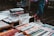 A street market table displaying paperback books for sale at £1 each. The table is filled with various books and DVDs, and a person wearing pink socks and white shoes is visible in the background.