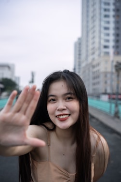 a woman is smiling and waving her hand