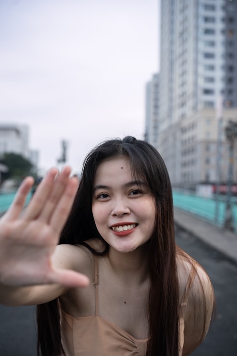 a woman is smiling and waving her hand