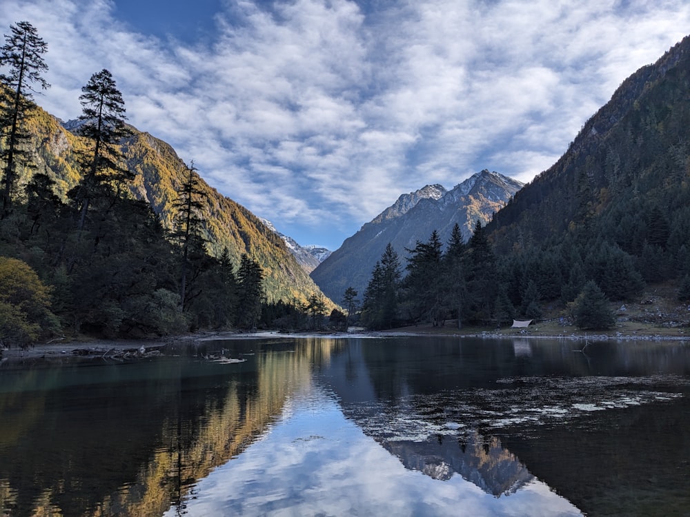 a lake surrounded by mountains under a cloudy sky