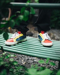 A pair of colorful rubber shoes resting on a wooden bench outdoors.
