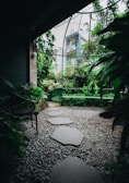 A serene modern garden with natural stone pathways and lush greenery under soft daylight.