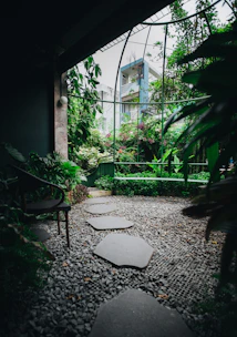 A serene modern garden with natural stone pathways and lush greenery under soft sunlight.
