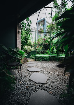 A serene modern garden with natural stone paths and lush greenery under soft sunlight.