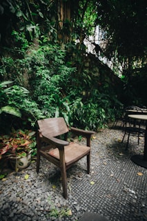 A plush outdoor chair pad resting on a wooden garden chair surrounded by greenery.