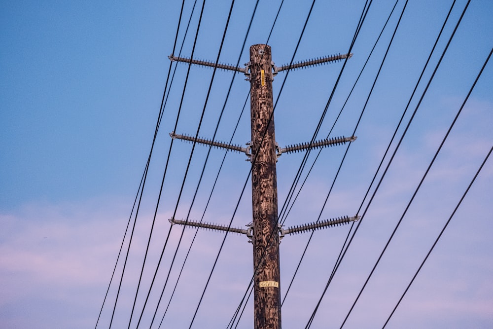 a telephone pole with many wires and a blue sky in the background