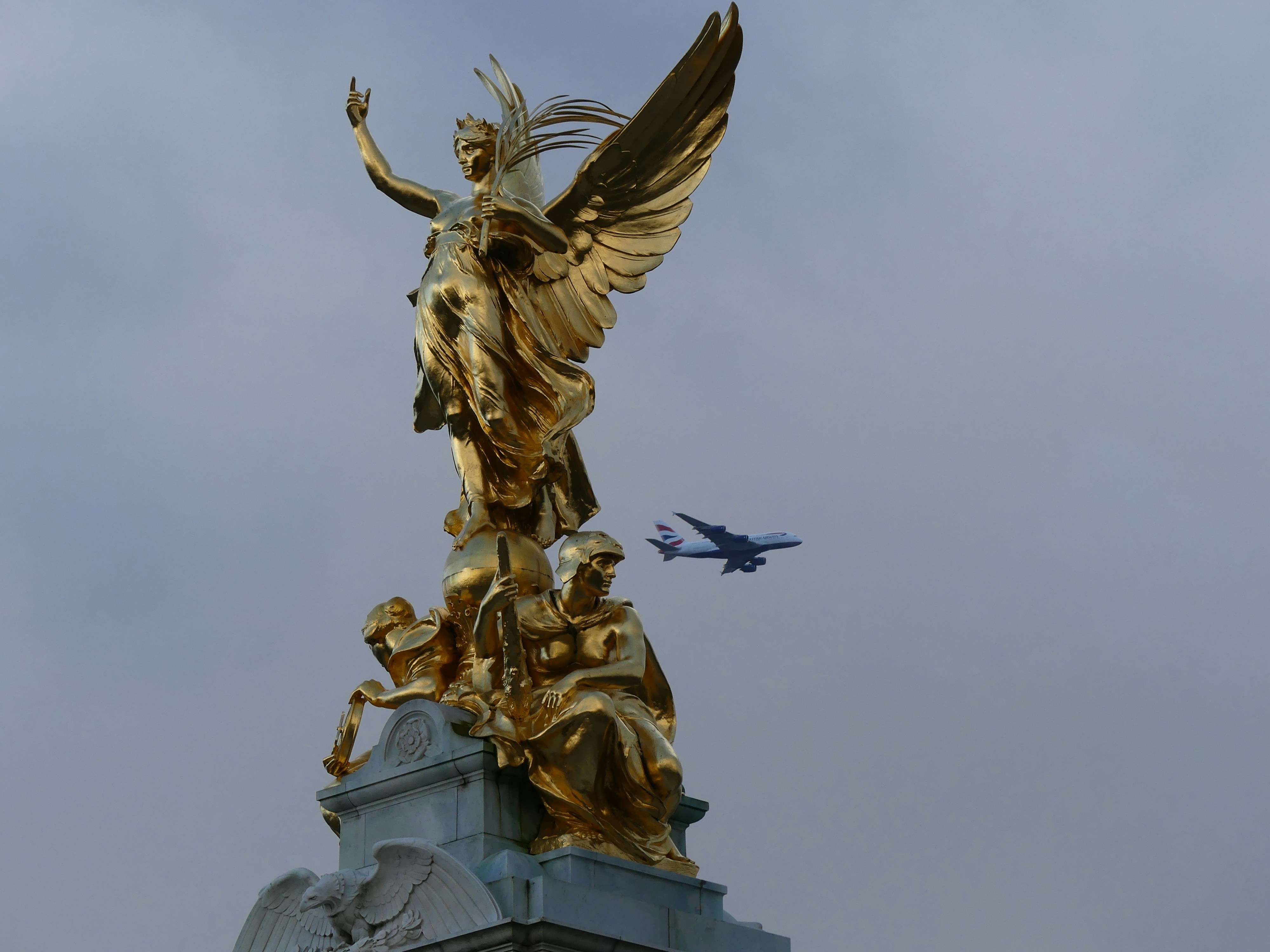a golden statue with a jet in the background