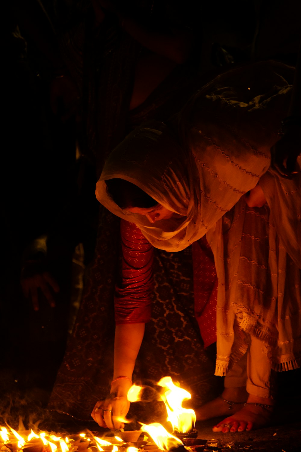 a woman lighting a candle in the dark