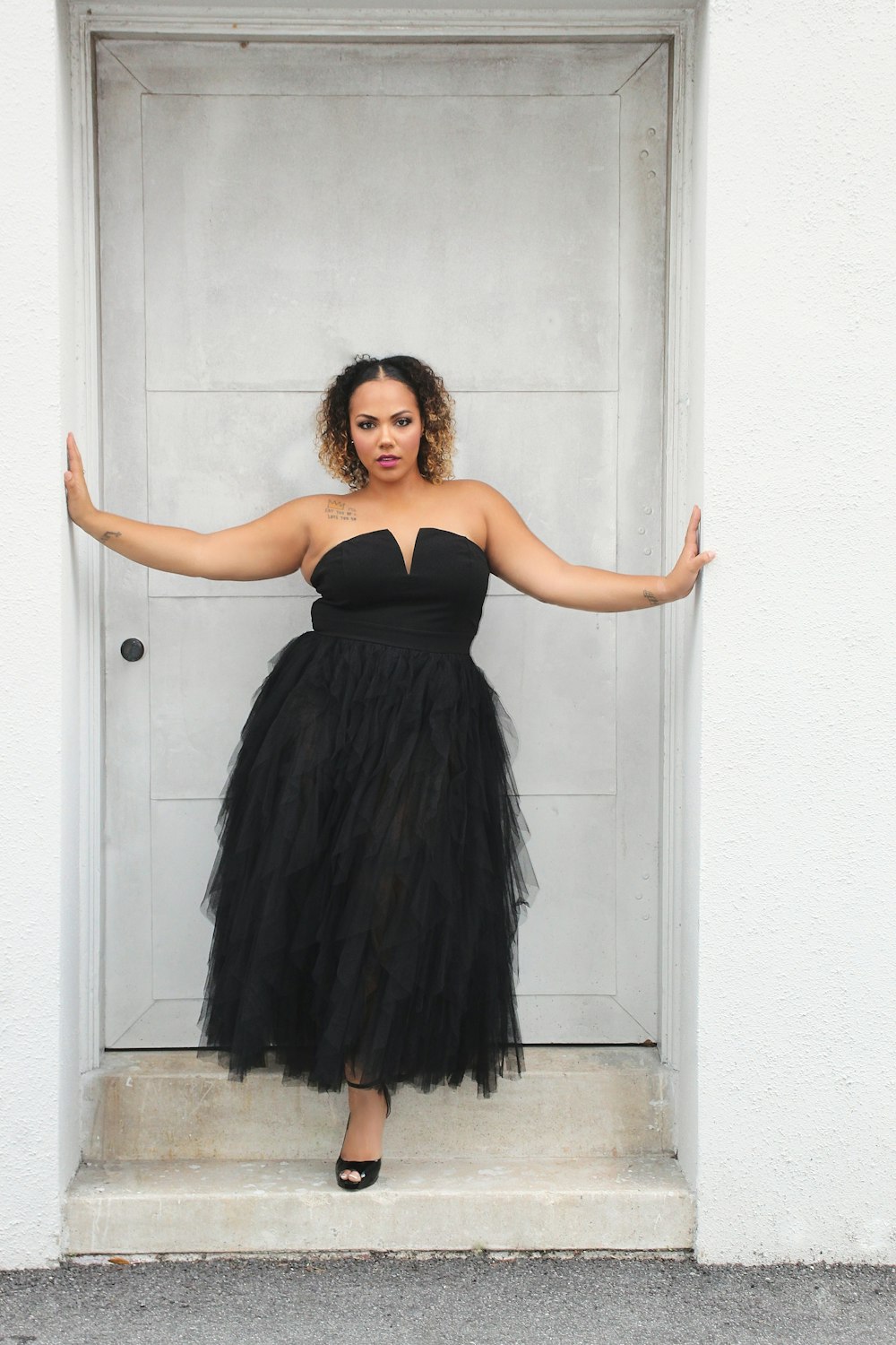 a woman in a black dress standing in front of a door