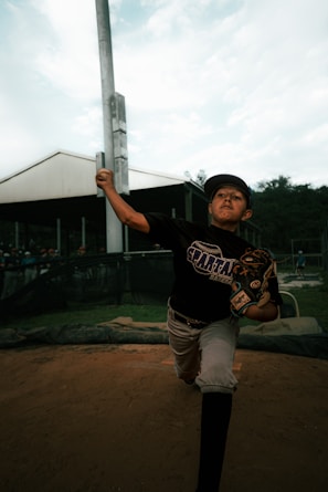a young boy holding a baseball bat on top of a field