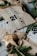 Several wrapped gift packages are decorated with printed ribbons and labels. Sprigs of evergreen are used as embellishments, creating a festive and natural look. The packages are wrapped in plain brown paper, and there are decorative elements like numbers and stars.