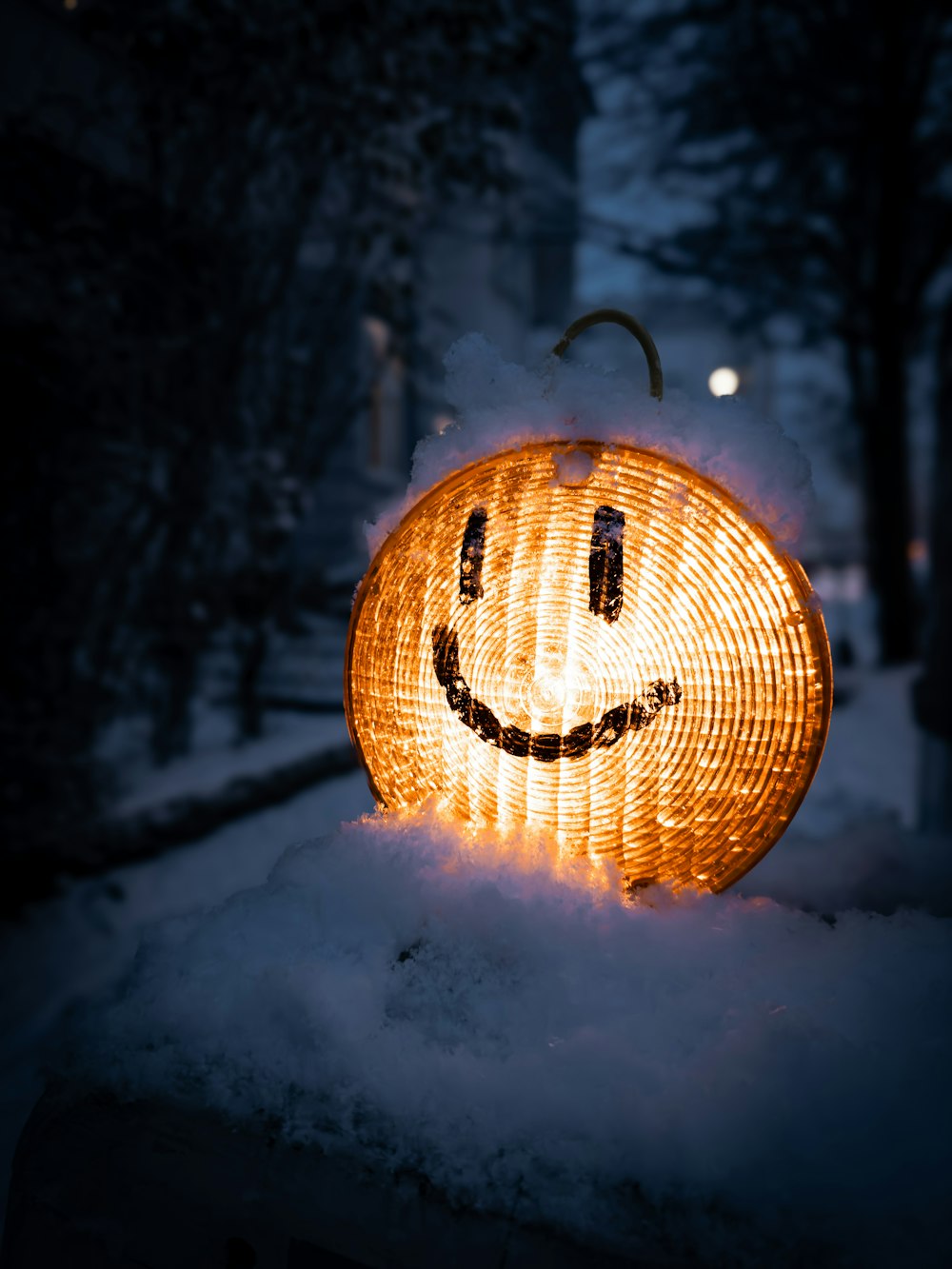 a lighted pumpkin sitting in the snow