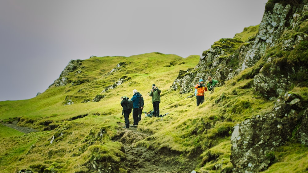 a group of people hiking up a grassy hill