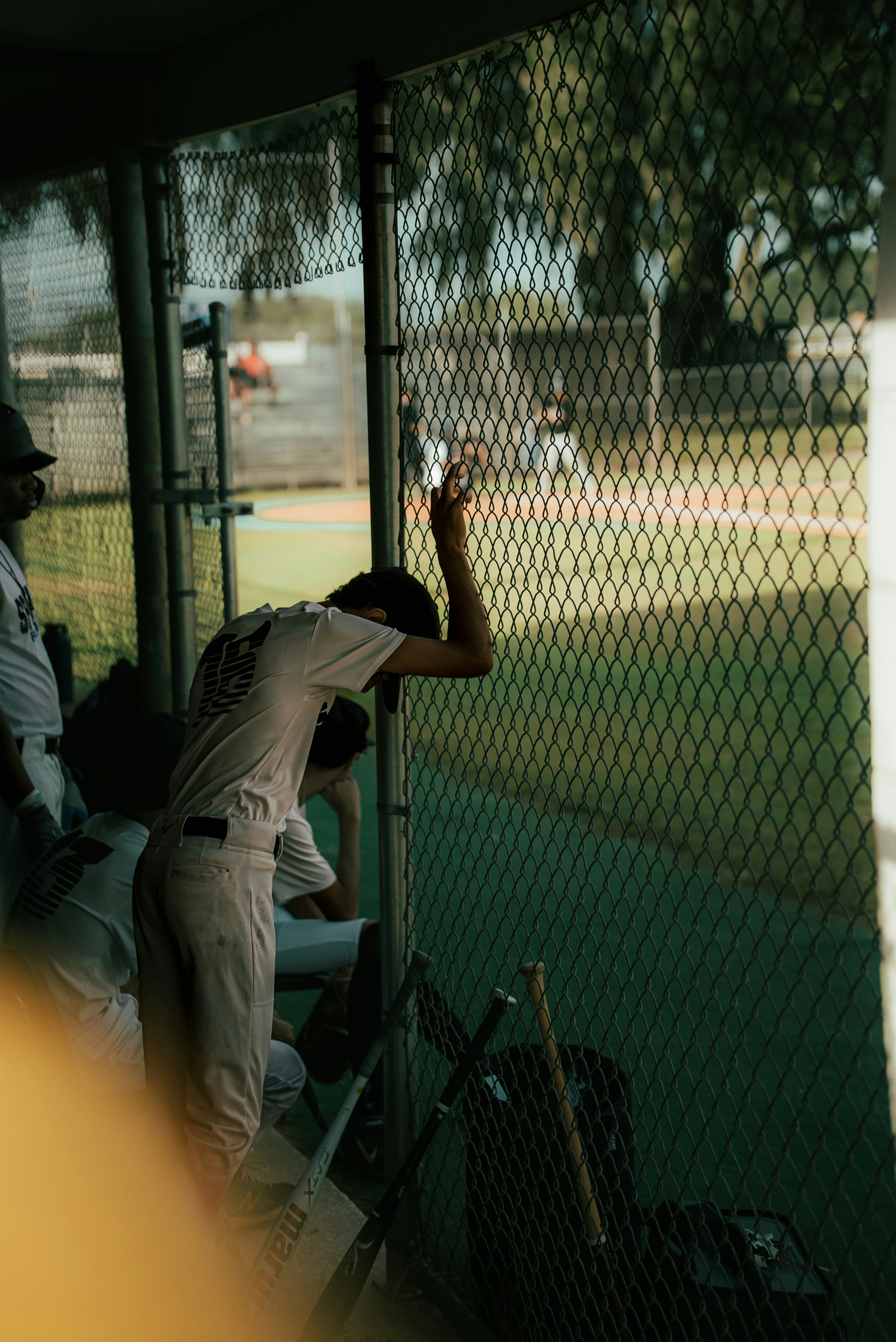 a baseball player leaning against a fence holding a bat