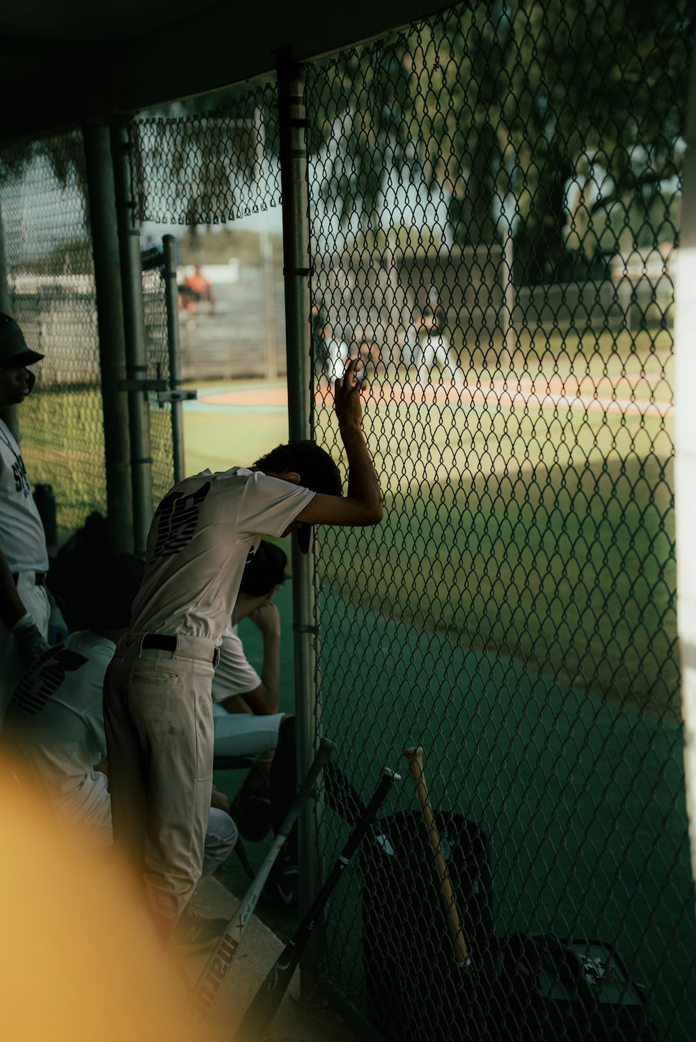 a baseball player leaning against a fence holding a bat