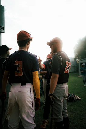 A coach and player reviewing baseball stats together on a tablet outdoors.