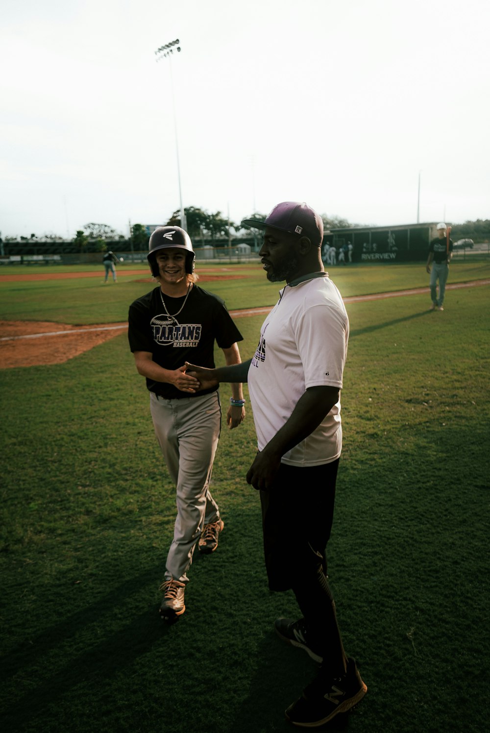 a couple of men standing on top of a baseball field