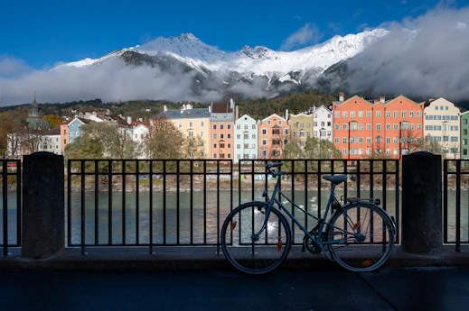 a bicycle parked next to a fence with mountains in the background