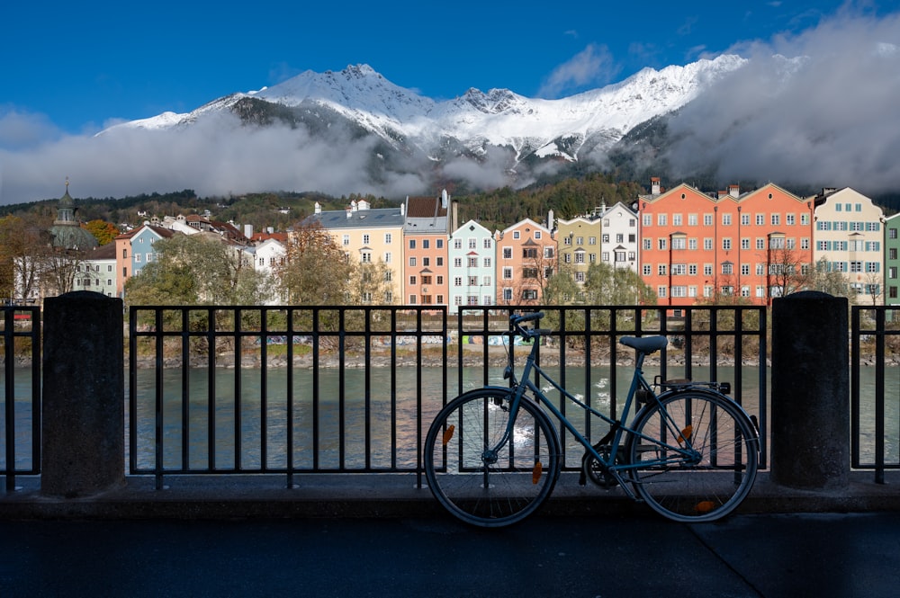 a bicycle parked next to a fence with mountains in the background