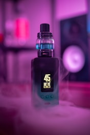 A futuristic box mod device illuminated in vibrant purple neon with smoky vapor swirling around