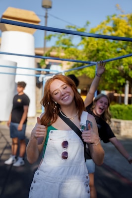 a woman in overalls giving a thumbs up