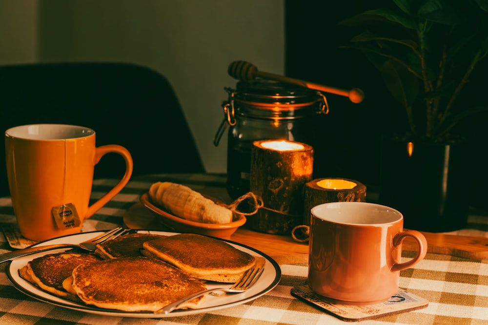 una mesa cubierta con un plato de panqueques junto a una taza de café