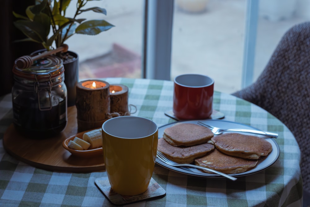 a table with a plate of pancakes and a cup of coffee