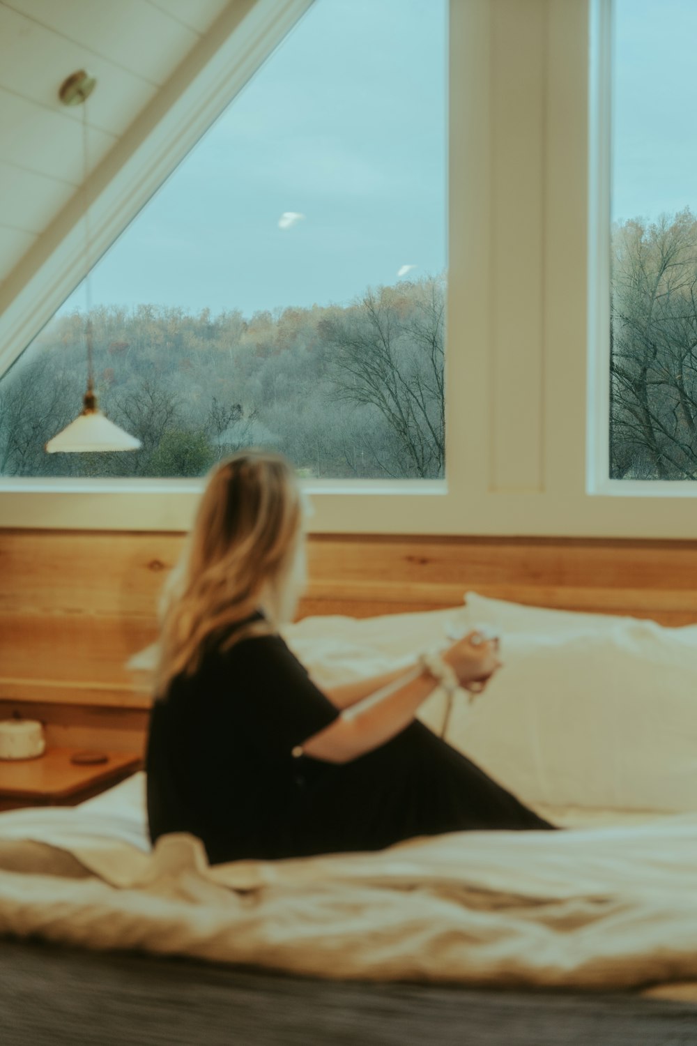 a woman sitting on a bed in front of a window