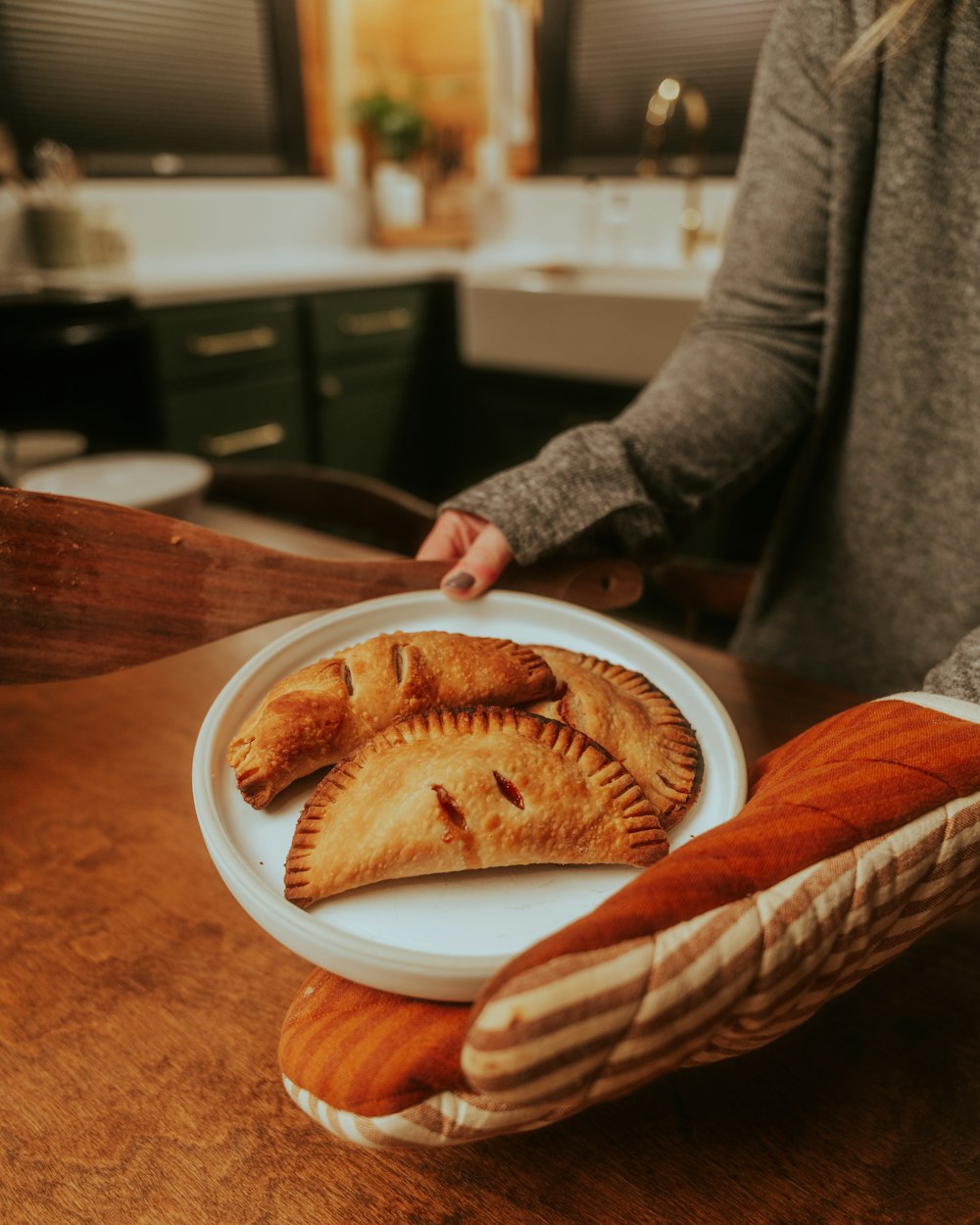 a woman holding a plate with pastries on it