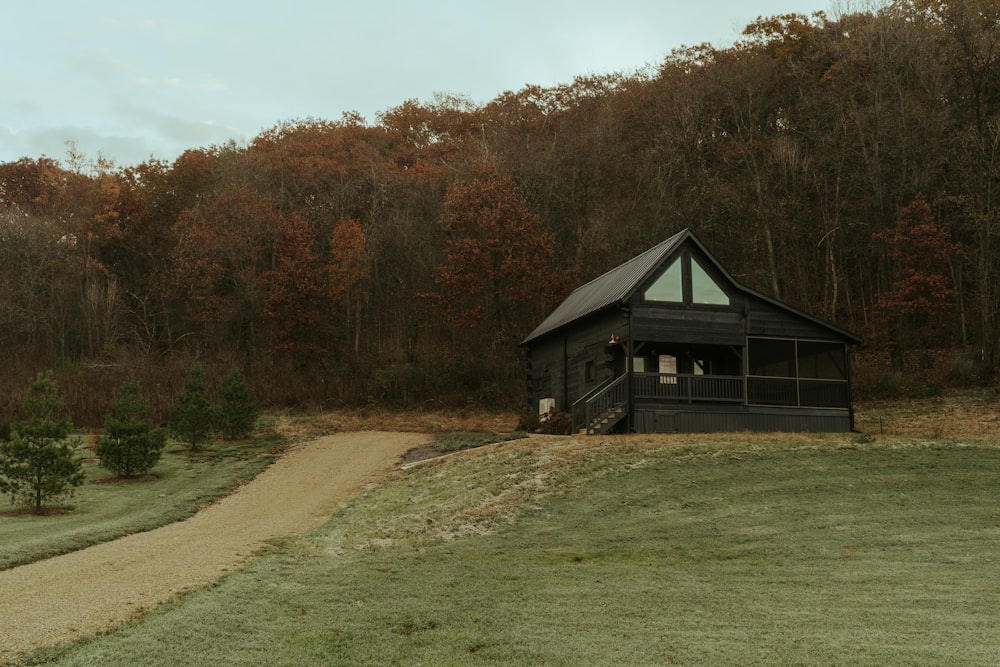 a small black cabin sitting on top of a lush green field