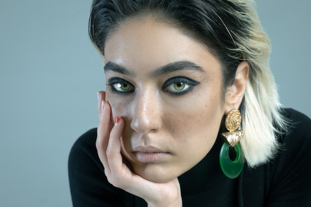 a woman with a black sweater and green earrings
