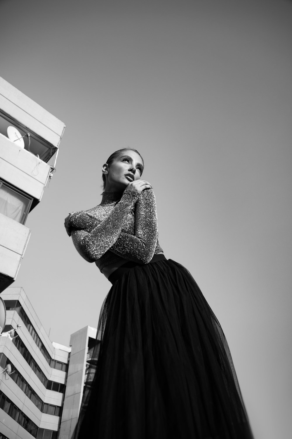 a woman in a long black dress standing in front of a tall building