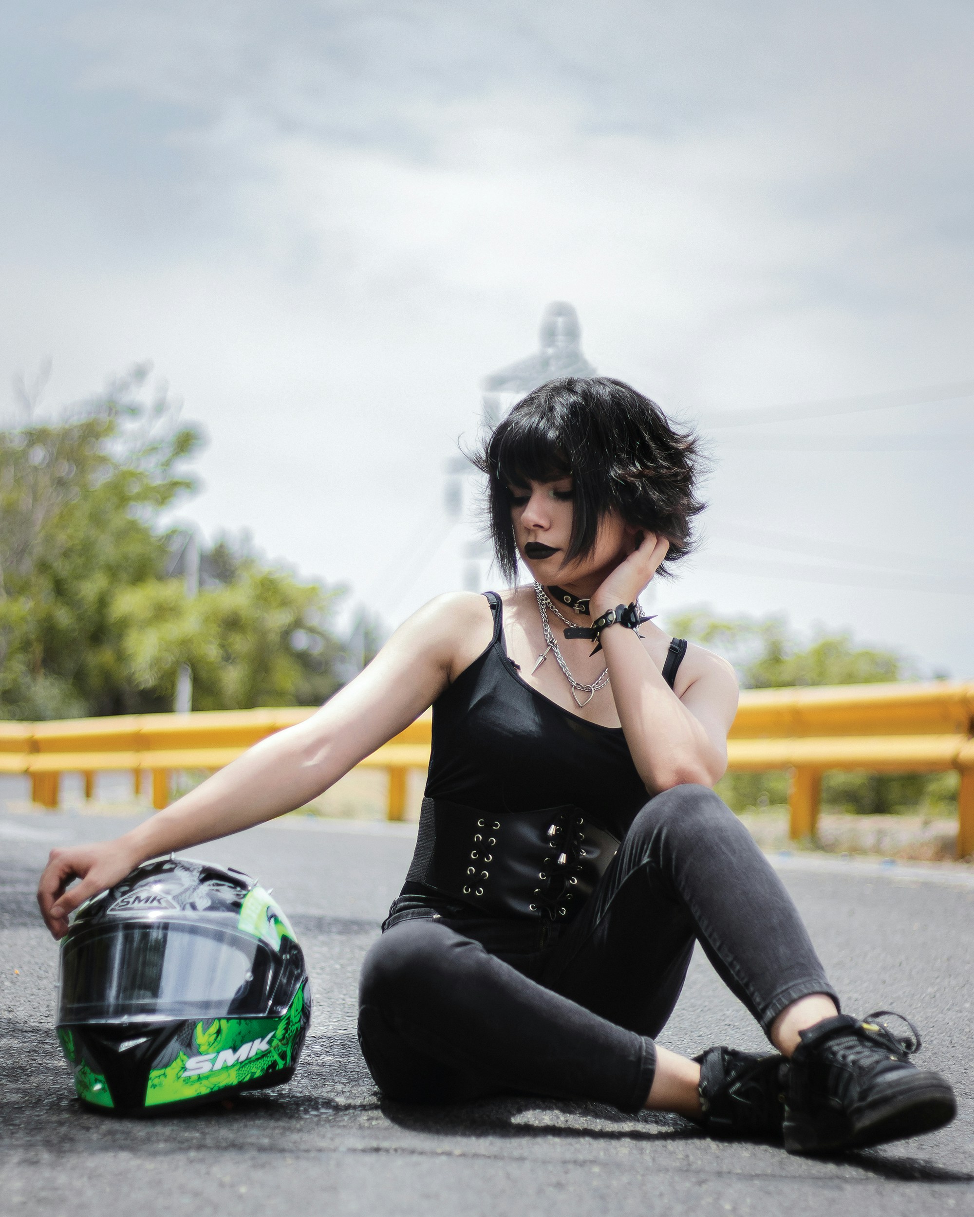 a woman sitting on the ground next to a motorcycle helmet