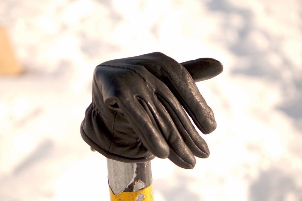 a pair of black gloves on top of a yellow pole