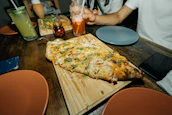 A colorful spread of Meltora’s handmade pizzas, fries, and refreshing beverages on a wooden table.