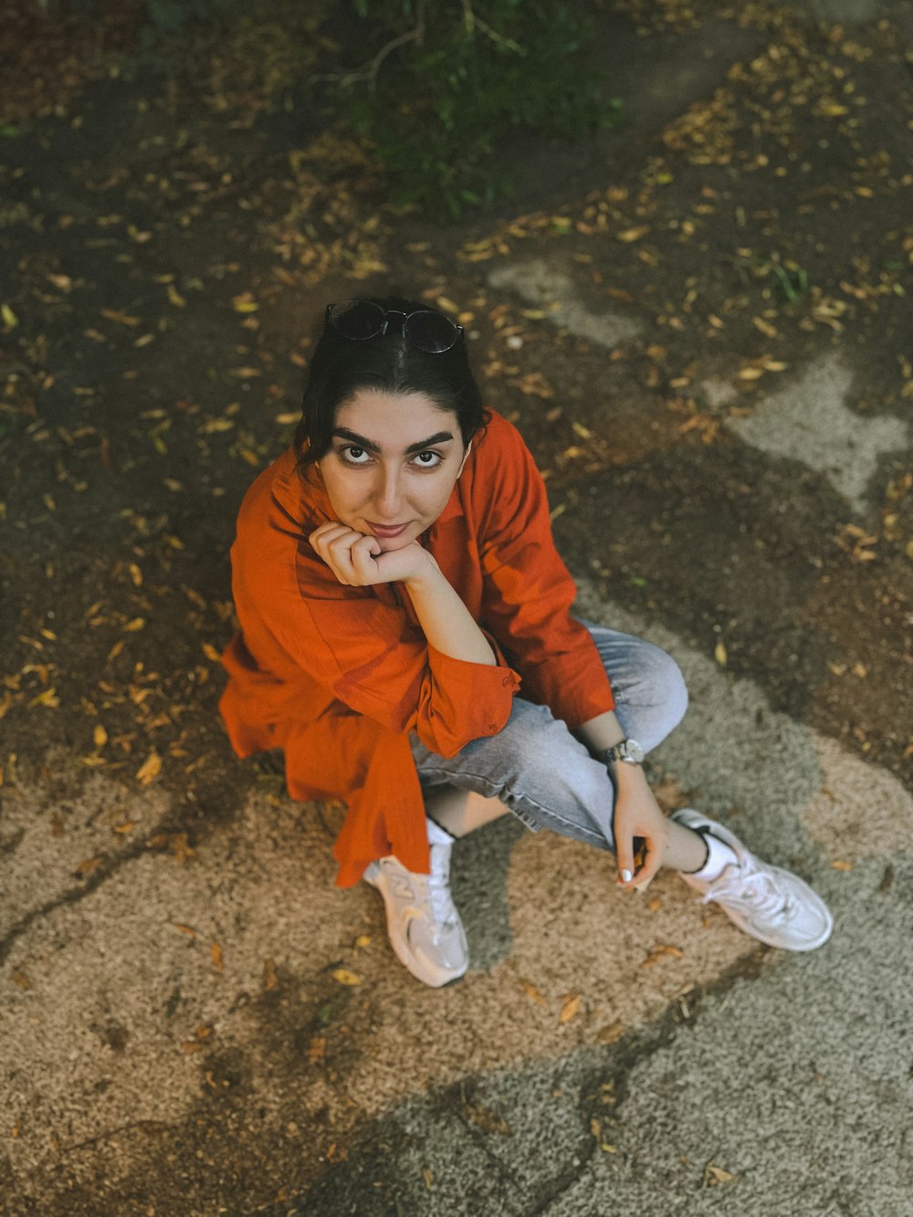 a woman sitting on the ground with her hand on her chin