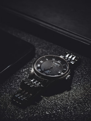 Elegant wristwatch with a sleek metal band displayed on a wooden surface.