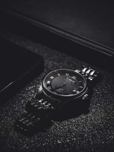 Elegant wristwatch with a sleek metal band resting on a marble surface with soft natural light